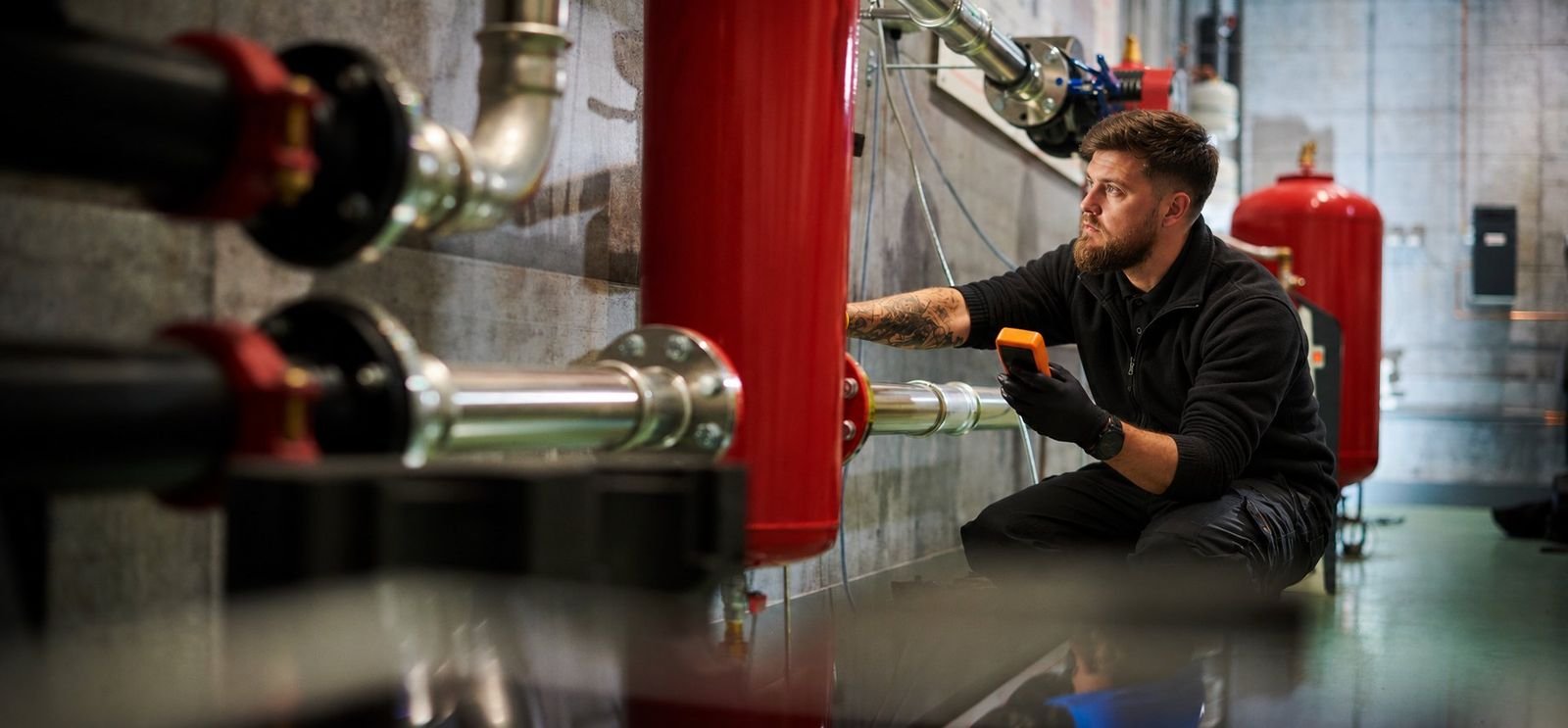 Plumber working on pipework in a commercial plant room
