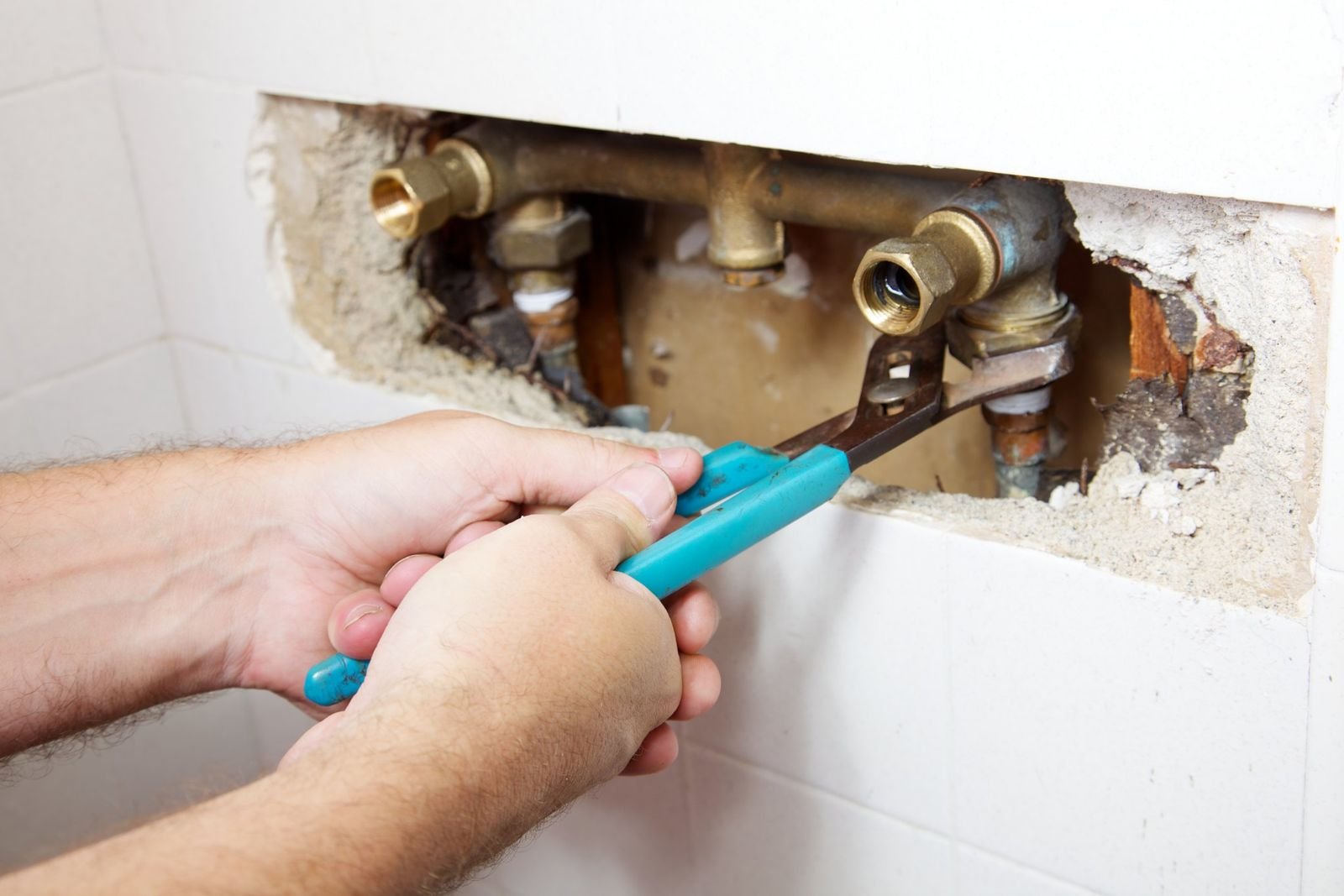 Plumber tightening isolation valves inside an opened wall